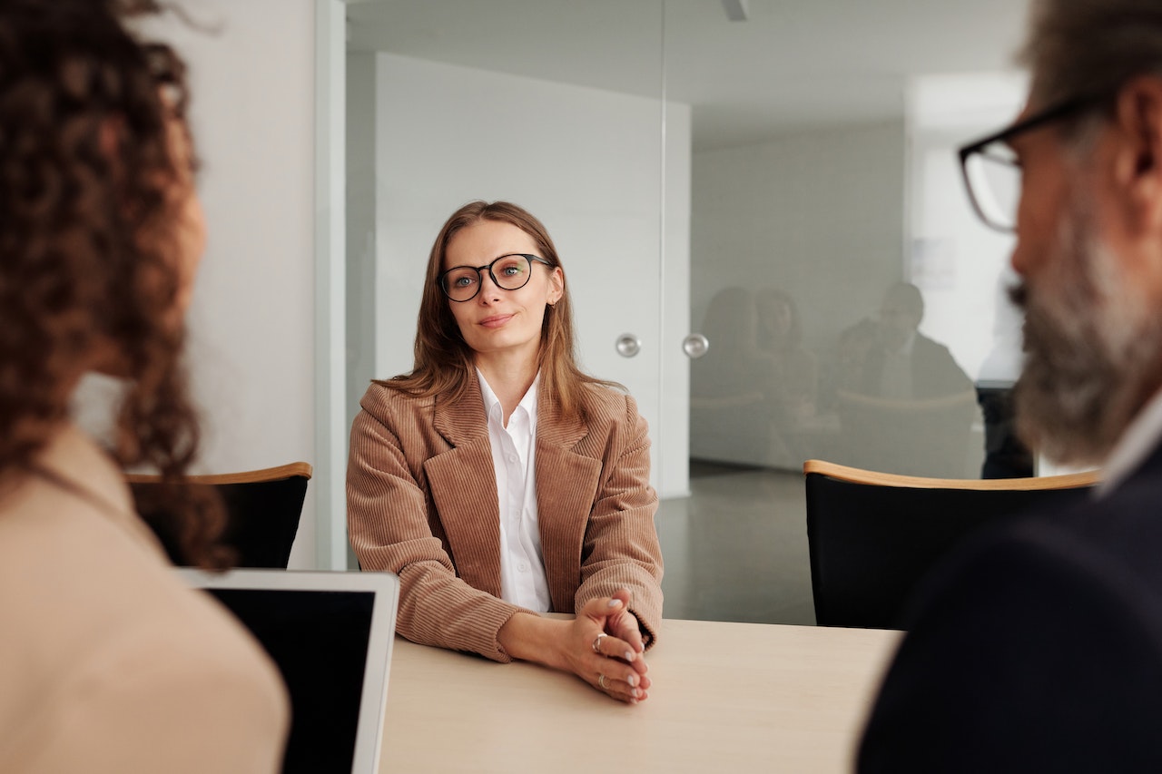 Woman in Brown Blazer seated beside Table in an Interview