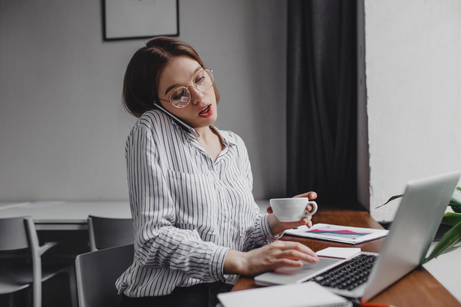 busy-office-worker-talking-phone-working-laptop-holding-cup-tea