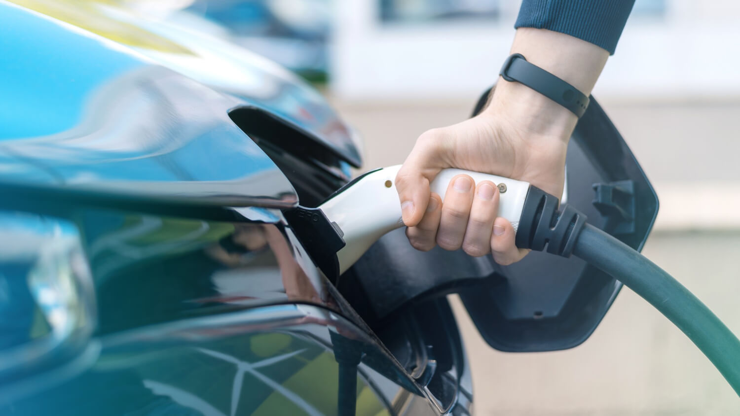 man-plugging-charger-into-electric-car-charge-station