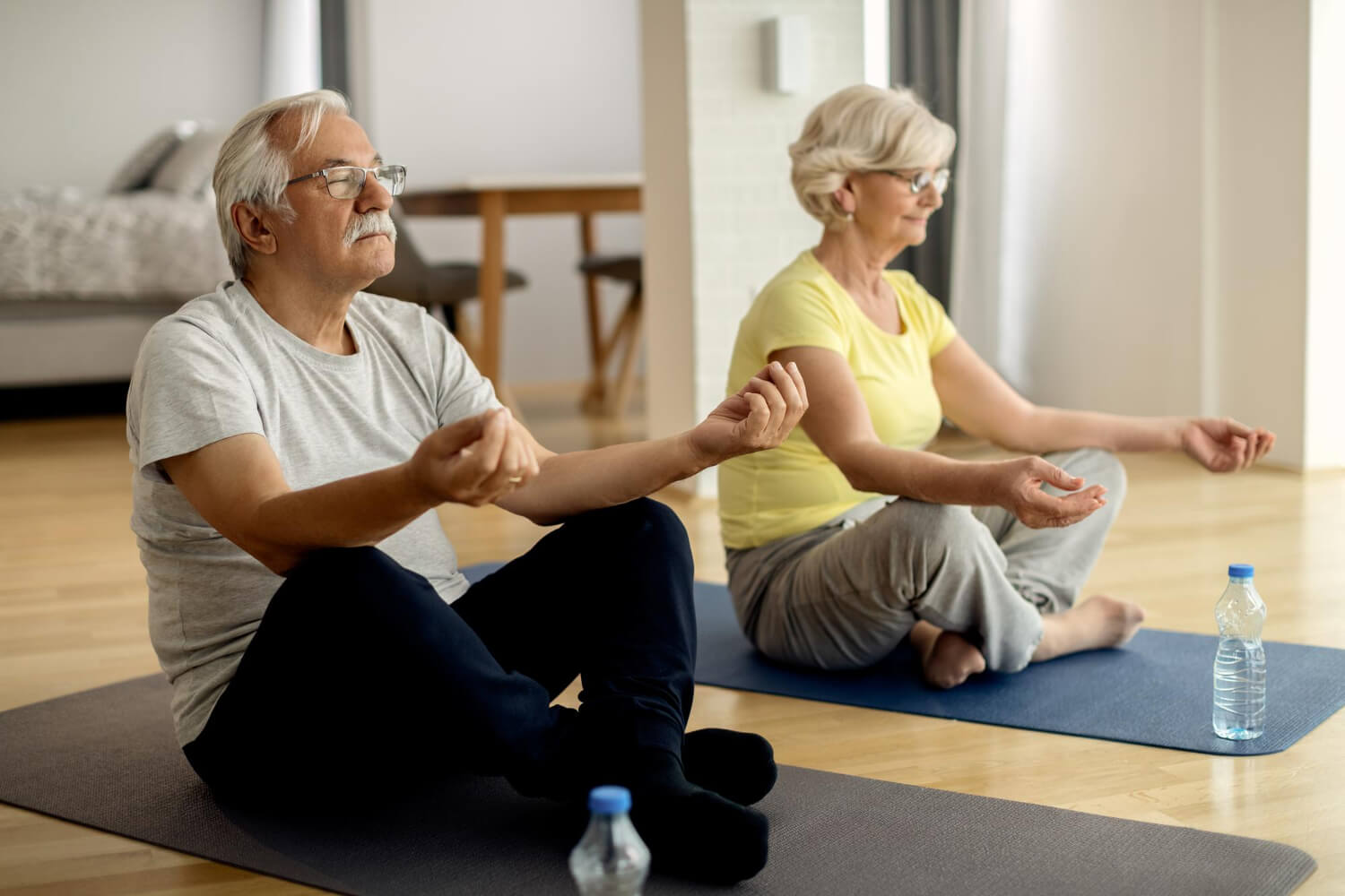 mature-couple-meditating-lotus-positing-home