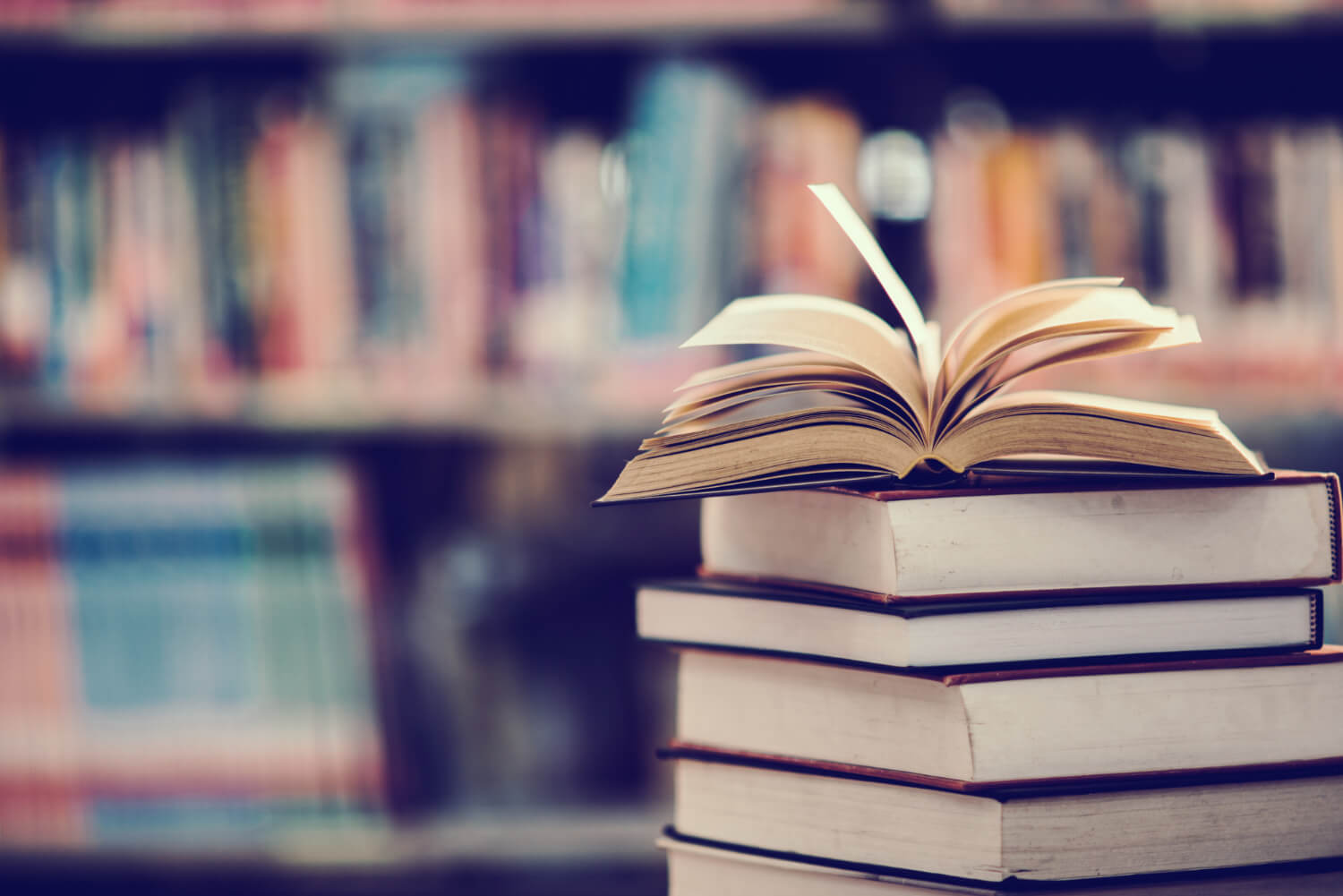 A-pile-of-books-stackeed-up-on-a-table-with-one-opened