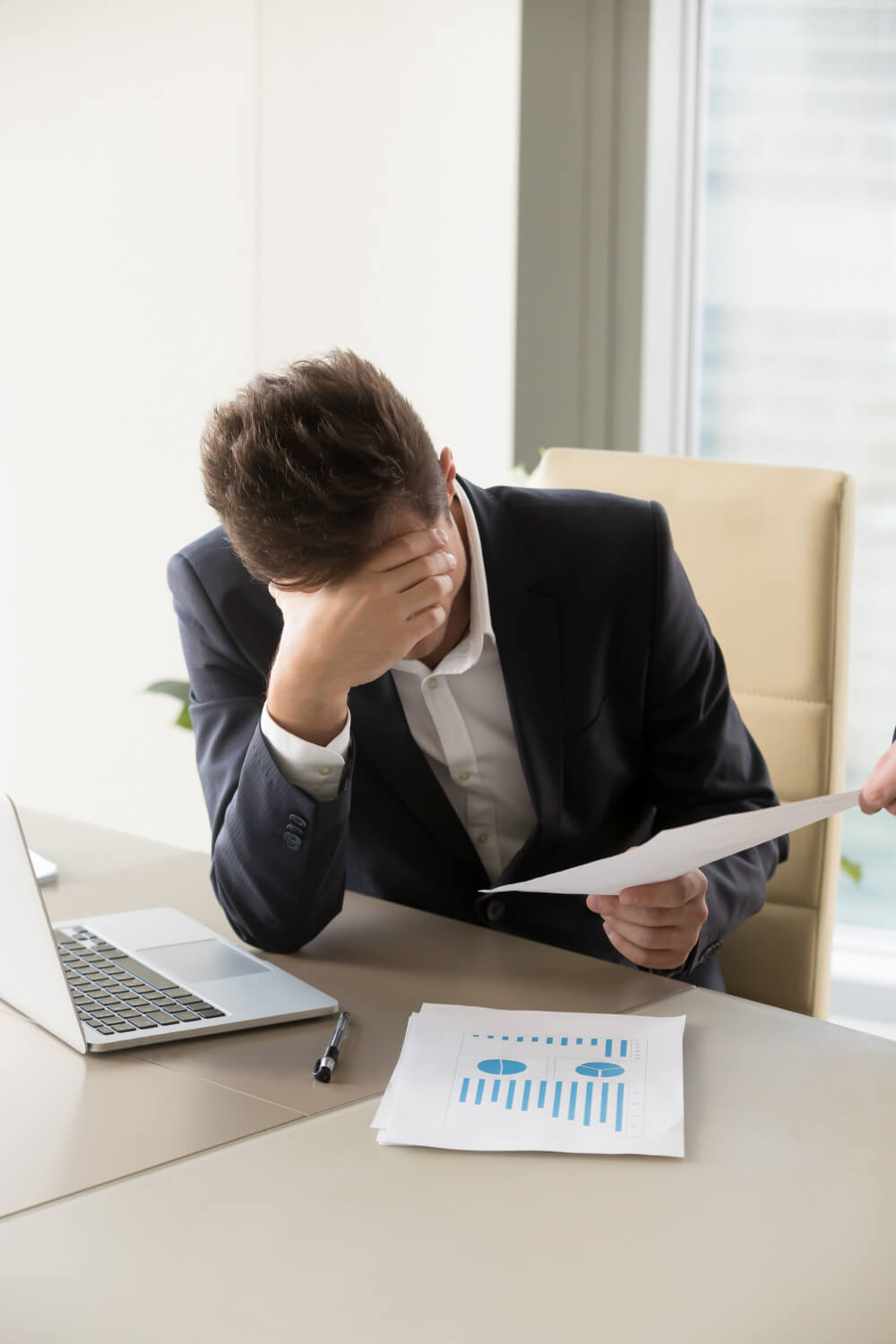 A man stressed out in his office with his hand on his head