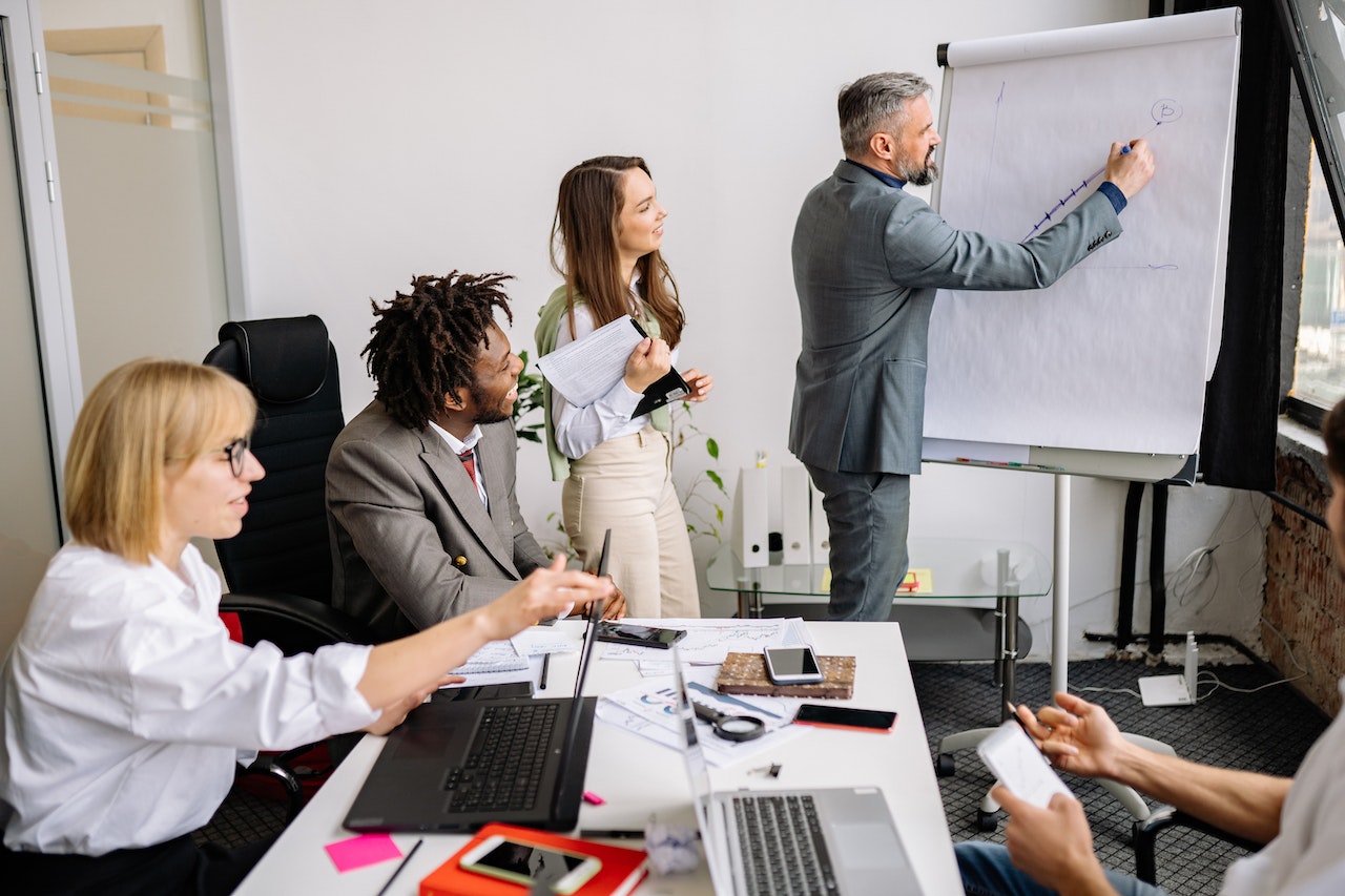 Executive addressing his employee while writing on a white board