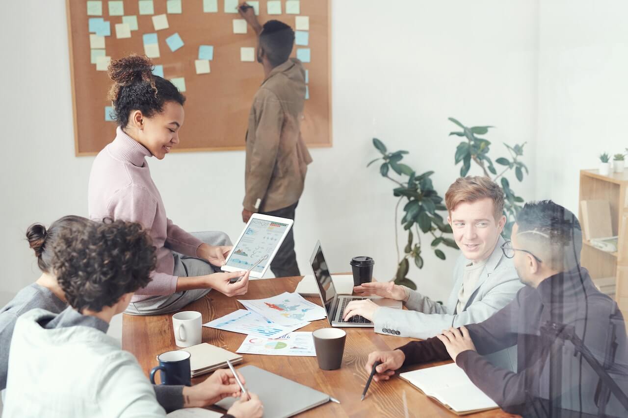 Lady sitting at the desk showing her colleagues a graph on a tablet device