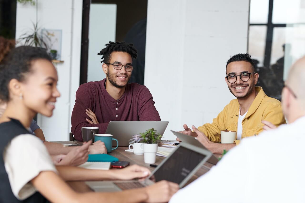 Smiling people using laptops in a meeting