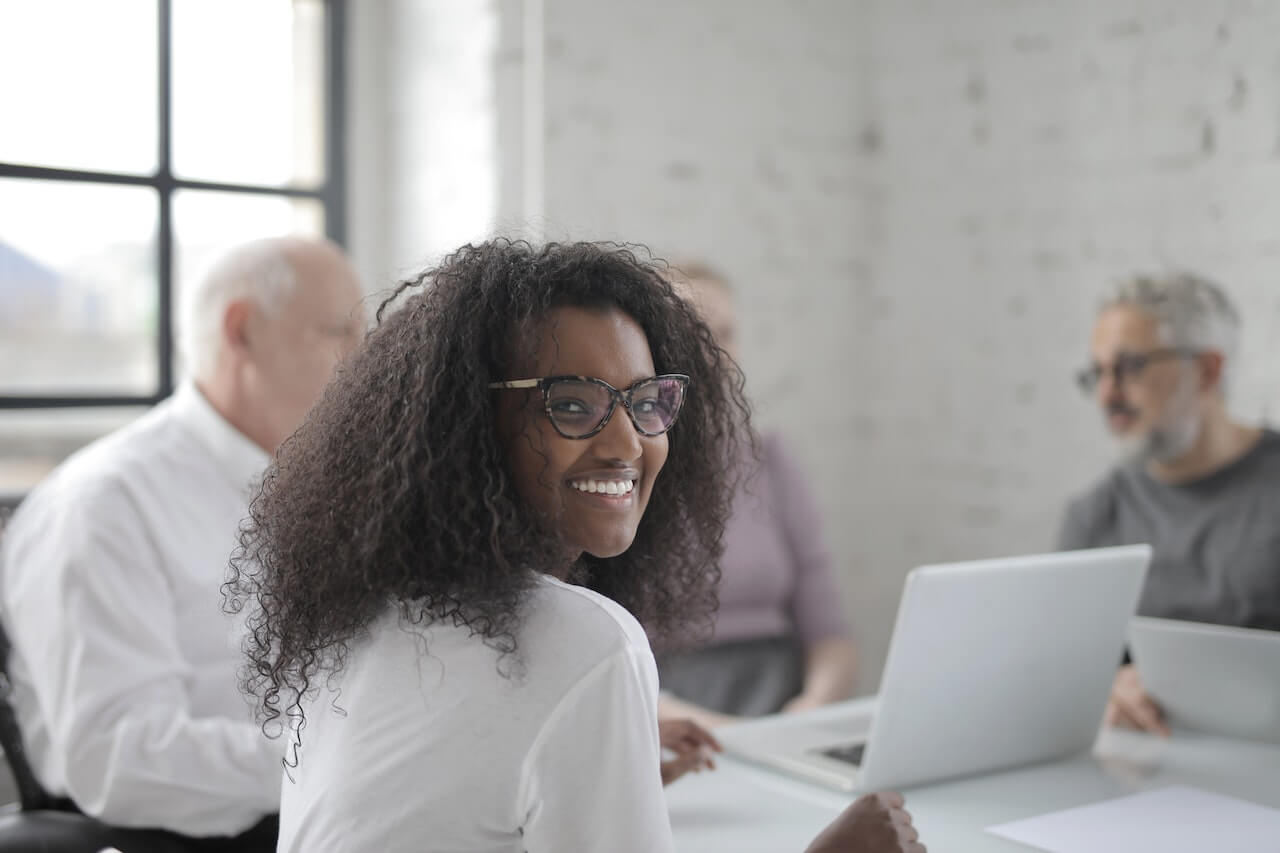 Smiling woman working in office with coworkers