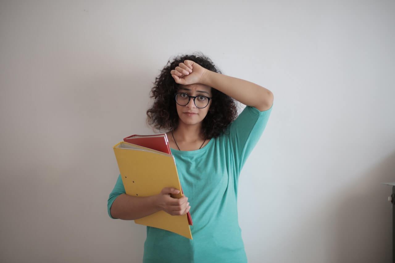 Tired adult woman with papers in light modern office