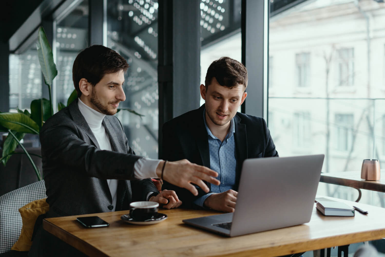 Two-businessmen-pointing-laptop-screen-while-discussing