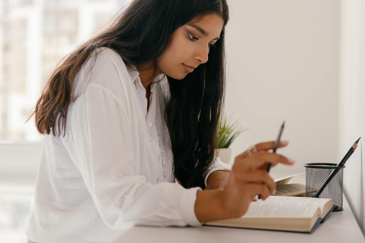 Woman in White Dress Shirt Writing on White Paper