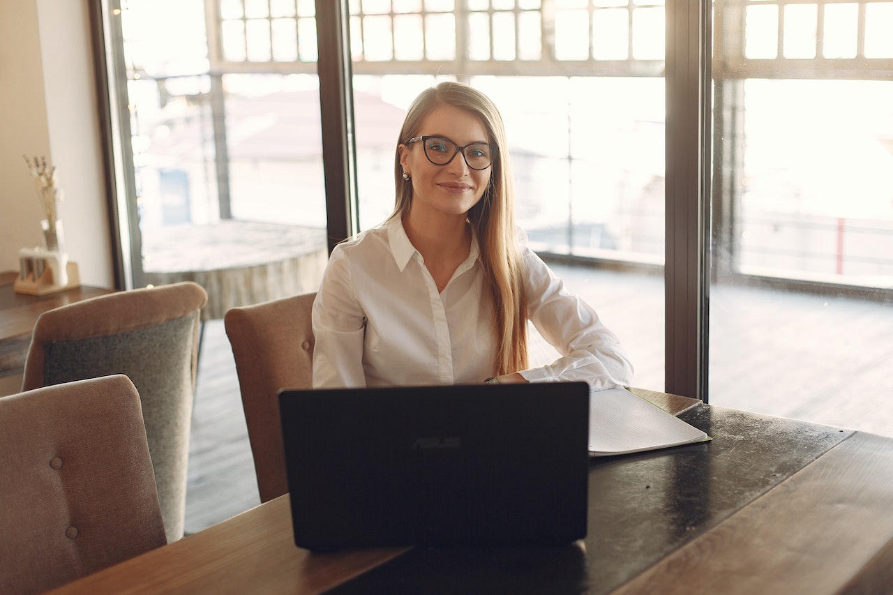 Woman in White Polo Shirt Sitting In Front Of A Black Laptop