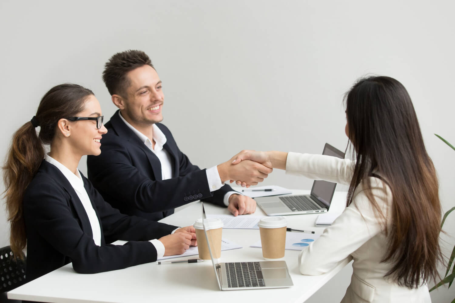 Friendly partners handshaking at group meeting