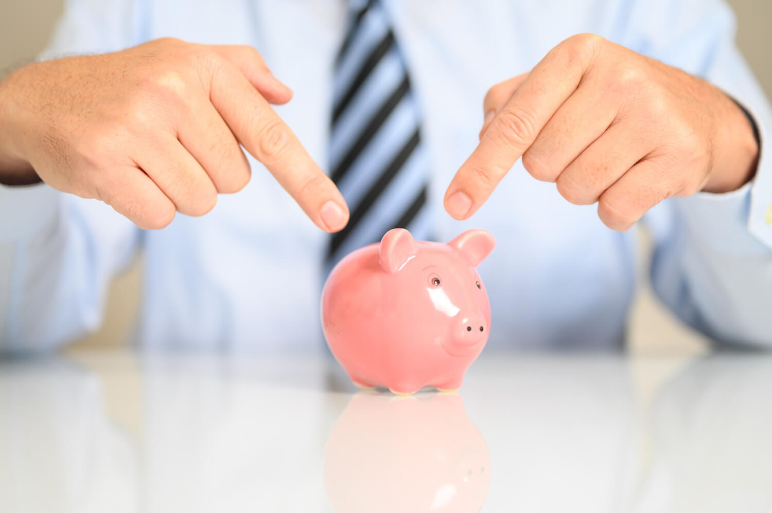 A businessman pointing to a piggybank