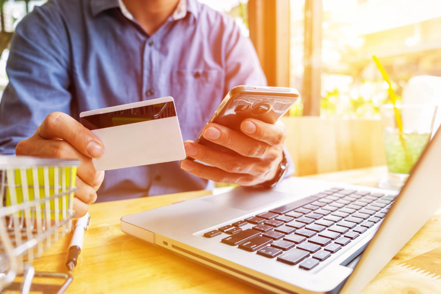 a man trying holding his ATM card shopping online on his laptop