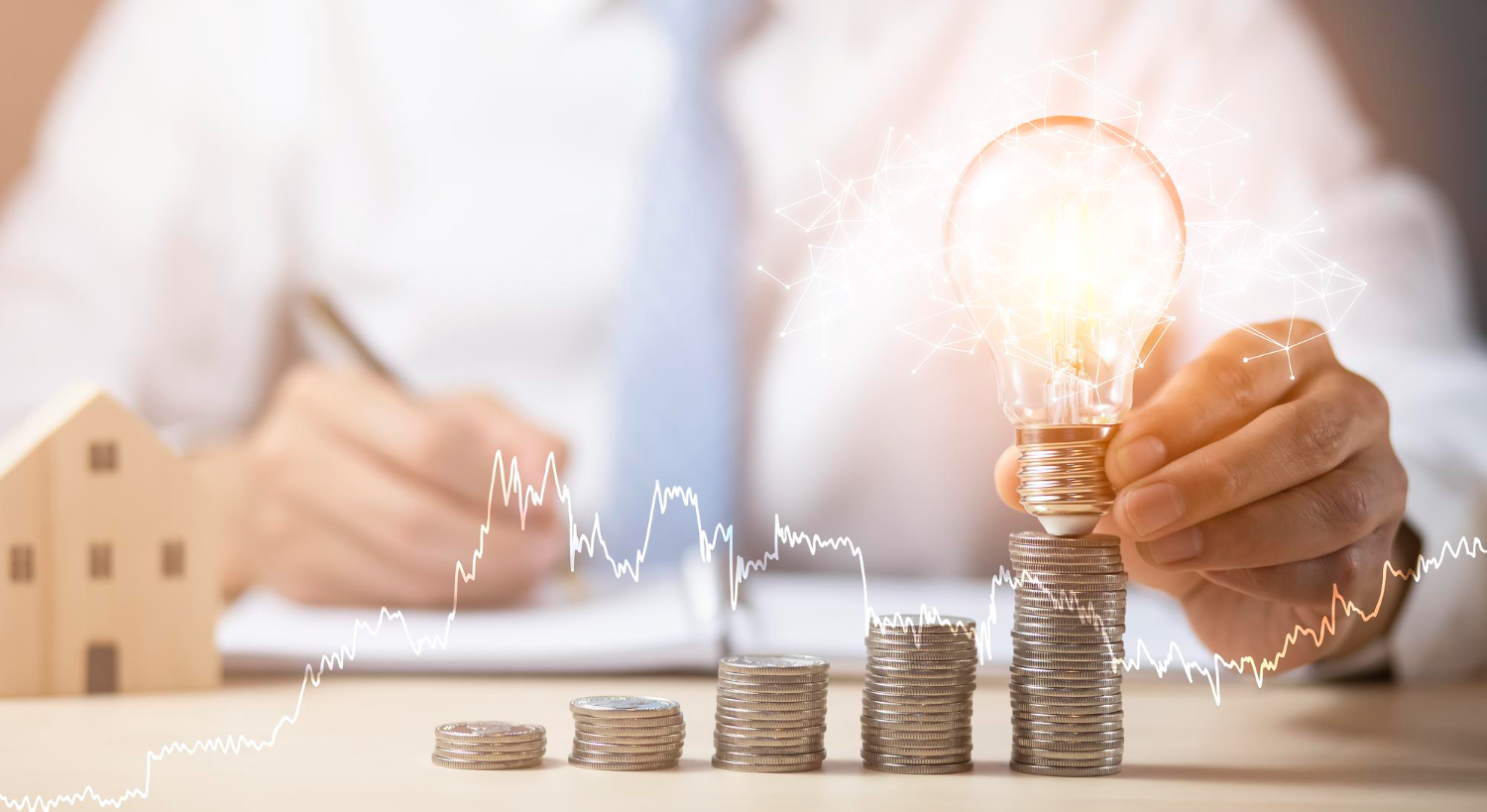 Stack of coins with a bulb on top on a desk